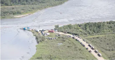  ??  ?? A crew works Friday to clean up the large oil spill on the North Saskatchew­an River near Maidstone, Sask.