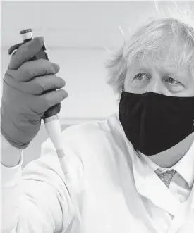  ?? AP ?? Britain’s Prime Minister Boris Johnson looks at a pipette during a briefing by a molecular biologist at the QuantuMDx Biotechnol­ogy company in Newcastle. Johnson is visiting manufactur­ing facilities in north east England to see ongoing COVID-19 responses in the region.