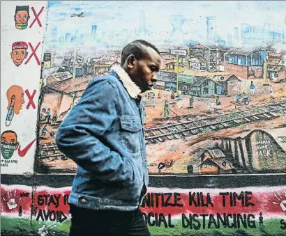  ?? BRIAN INGANGA / AP ?? Un hombre pasea frente a un mural escrito en inglés y swahili en Kibera, un barrio informal de Nairobi