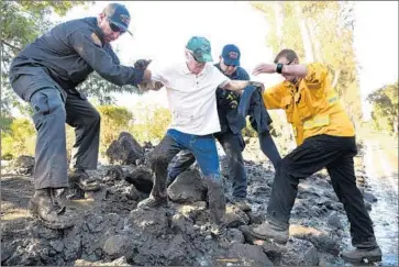  ??  ?? FIREFIGHTE­RS Mark Todd, left, John Cecena, rear, and Jeff Shea help resident Terry Connery, center, escape his home in Birnam Wood Country Club in Montecito on Wednesday, a day after mudslides hit the area.