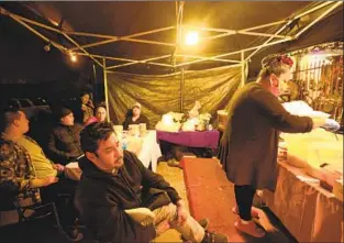  ?? Genaro Molina Los Angeles Times ?? MARIA ROSA GARCIA, right, sells tacos in front of her South L.A. home to make ends meet. Marco Ortiz, foreground, and other performers spend their nights at the makeshift taco stand.