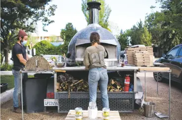  ?? PHOTOS BY OLIVIA HARLOW/THE NEW MEXICAN ?? Crosky, left, and Chamisa Going prep ingredient­s and tend to the fire at Tender Fire last month outside El Rey Court.