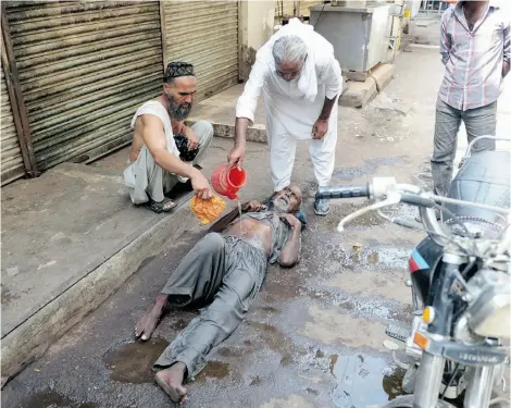  ?? RIZWAN TABASSUM/AFP/GETTY IMAGES ?? A Pakistani resident helps a heatstroke victim at a market area during a heat wave in Karachi on Tuesday.