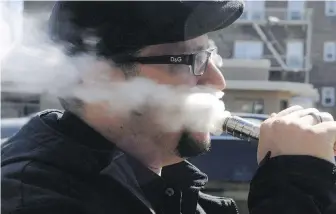  ??  ?? A man vapes outside a store selling electronic cigarettes in New Jersey. The Canadian government says it plans to introduce legislatio­n this fall to regulate vaping.