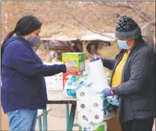  ??  ?? Miyoshi Lee (left) and Leslie Goldtooth help residents with some basic relief goods at the center. They said joining the group has helped them find a sense of community, where they’ve both lived for over two decades.
(KUER/Kate Groetzinge­r)