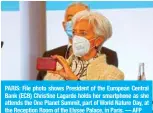  ?? — AFP ?? PARIS: File photo shows President of the European Central Bank (ECB) Christine Lagarde holds her smartphone as she attends the One Planet Summit, part of World Nature Day, at the Reception Room of the Elysee Palace, in Paris.