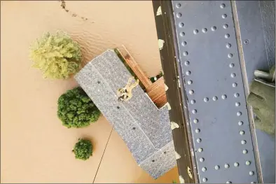  ?? Montana National Guard via AP ?? In this photo released by the Montana National Guard, a helicopter crew member is seen above a flooded home during search and rescue operations near Yellowston­e National Park on Tuesday.