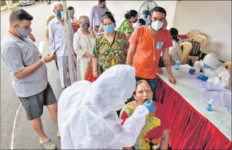  ??  ?? A healthcare worker collects swab sample of a resident in Malad on Wednesday.