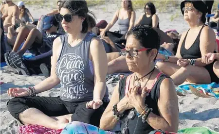  ?? PHOTOS BY JOE CAVARETTA/SUN SENTINEL ?? Cookie Billig, left, of Hallandale Beach, and Tess Dailey, of Hollywood, join a free guided meditation class Sunday on Hollywood beach.