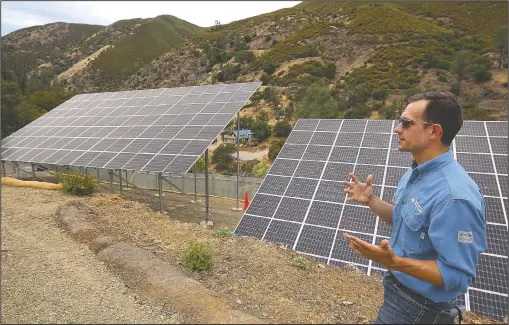  ?? (AP/Gary Kazanjian) ?? Program lead Bennett Chabot stands by Pacific Gas & Electric’s new Remote Grid Initiative site near Yosemite National Park in Briceburg, Calif. When a wildfire tore through Briceburg nearly two years earlier, the tiny community on the edge of Yosemite National Park lost the only power line connecting it to the electrical grid. Rather than rebuilding poles and wires over increasing­ly dry hillsides, which could increase the risk of equipment igniting catastroph­ic fires, the nation’s largest utility decided to give Briceburg a self-reliant power system.