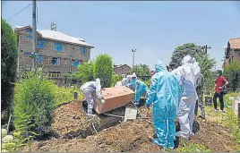  ?? WASEEM ANDRABI/ HT ?? Medical staff and relatives a Covid-19 victim bury his coffin into a grave while wearing personal protective equipment. The patient died at Safa Kadal in Srinagar on Saturday.