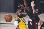  ?? MARK J. TERRILL — THE ASSOCIATED
PRESS ?? The Lakers’ LeBron James passes the ball while pressured by the Heat’s Bam Adebayo (13) during Game 1 on Wednesday.