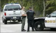  ?? WILFREDO LEE — THE ASSOCIATED PRESS ?? Law enforcemen­t officers gather at the entrance of Silver Lakes Rotary Nature Park, Friday, in Davie, Fla. Someone called police after seeing a woman who was walking her dog in the park being dragged into a lake by an alligator.