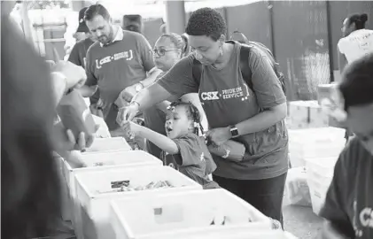  ?? KIM HAIRSTON/BALTIMORE SUN ?? Ashley Stowers of Richmond, Va., and her daughter, Camren Stowers, 4, are among the volunteers packing 10,000 care pouches for Baltimore’s first responders at the B&O Railroad Museum. Three generation­s of the Stowers family participat­ed in the event.