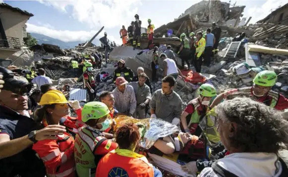  ?? MASSIMO PERCOSSI/THE ASSOCIATED PRESS ?? A woman is carried on a stretcher by rescuers in Amatrice, Italy, after a 6.1 earthquake struck there early Wednesday morning. The quake was felt across a broad section of central Italy.