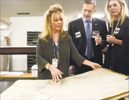  ?? Tyler Sizemore / Hearst Connecticu­t Media ?? Clerk Jeannie Laughlan, left, shows a book of town maps from 1938 to Stamford’s Paul and Aga Senecal during Thursday’s open house at the City and Town Clerk’s Office in Stamford. The office held an open house to explain its services and display Stamford’s historical documents and maps from the archives.