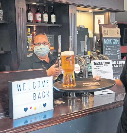  ??  ?? Staff at The Victoria pub in Whitley Bay welcome back customers as they serve the first pints post-lockdown down south