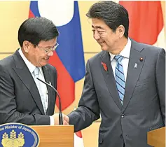  ?? — Reuters photo ?? Laotian Prime Minister Thongloun Sisoulith (left) and Shinzo Abe shake hands at Abe’s office inTokyo.Thongloun is in Japan to attend the10th Mekong-Japan Summit.