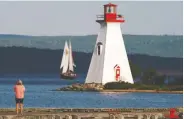  ?? CARLO ALLEGRI / REUTERS ?? A woman takes photos of a lighthouse in Baddeck, Nova Scotia, where housing prices have seen substantia­l gains.