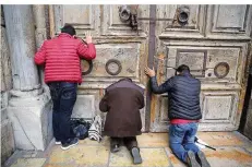  ?? FOTO: ILLEAN/DPA ?? Besucher beten vor der geschlosse­nen Tür der Grabeskirc­he, der heiligsten Stätte des Christentu­ms, in der Altstadt von Jerusalem.