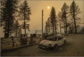  ?? AP PHOTO/NOAH BERGER ?? As the Camp Fire burns nearby, a scorched car rests by gas pumps near Pulga, Calif., on Sunday.