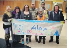  ??  ?? Members of a sponsoring group aided by the Refugee Program of the Anglican Synod of the Diocese of British Columbia prepare to greet refugees at Victoria Internatio­nal Airport.