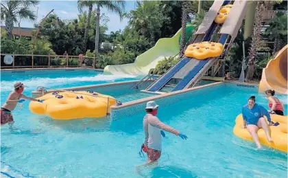  ?? DEWAYNE BEVIL/ORLANDO SENTINEL ?? A Volcano Bay worker sprays disinfecta­nt on a raft while another helps visitors disembark from the Maku Puihi slide at the water park this week.