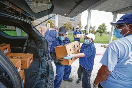  ?? Photos by Steve Gonzales / Staff photograph­er ?? Jesse Alfaro, left, and Rosaura Diaz, center load boxes of food Monday as the Houston Independen­t School District reopened its curbside summer meals program at Lawson Middle School. HISD will distribute food at 12 strategica­lly located sites.