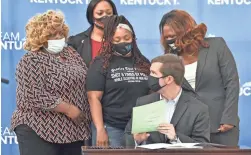  ?? TIMOTHY D. EASLEY/AP ?? Kentucky Gov. Andy Beshear talks with Tamika Palmer, mother of Breonna Taylor, back row center, after the signing Friday.