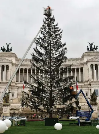  ?? ALBERTO PIZZOLI/AFP/GETTY IMAGES ?? A worker removes the star decoration on top of the Christmas tree of the city of Rome known as the “Spelacchio” (which translates as “Mangy” or “Baldy”) Tuesday in Piazza Venezia in Rome.