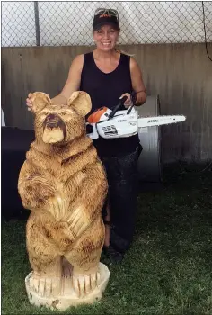  ??  ?? Chainsaw carving artist Shari Staiduhar poses with a wooden bear, which stands about 4 feet tall, on July 28 at the Lake County Fair. She carved the bear during the first day of the fair on July 27.