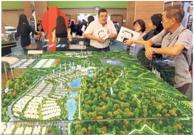  ??  ?? Gleaning informatio­n: Potential homebuyers listening to the explanatio­n on the prospects and benefits of the Gamuda Land township developmen­t.
