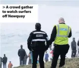  ??  ?? > A crowd gather to watch surfers off Newquay