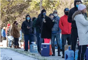  ?? Associated Press ?? ■ Devin Hodge and Nate Rowe wait in line to fill up their containers with water Friday at Meanwhile Brewing Company in Austin during a citywide boil water notice caused by the winter storm. The brewery gave away all 4,000 gallons of their water to people in need on Thursday and Friday.