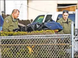  ?? Gary Coronado Los Angeles Times ?? OFFICIALS WITH the Tulare County Sheriff’s Office remove a body from a property where six people were killed Monday in the farming town of Goshen.