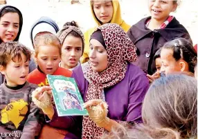  ?? ?? Children surround Asma as she tells them stories to help them cope with the mental distress caused by the war, February 2024 (MEE/Mohammed Baker)