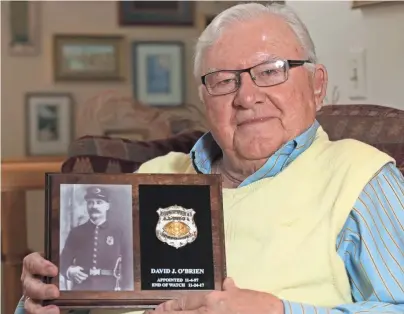  ?? MILWAUKEE JOURNAL SENTINEL MARK HOFFMAN / ?? John O’Brien holds a memorial plaque for his grandfathe­r, David J. O’Brien, at his home in Fond du Lac. His grandfathe­r, a Milwaukee detective, was killed in the Central Police Station bombing of 1917.