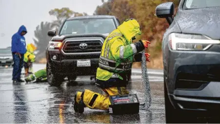  ?? Watchara Phomicinda / Associated Press ?? A snow chain installer assists a vehicle near Running Springs, Calif., on Saturday. After months of hot weather that fueled immense wildfires, the first thundersto­rm of the season brought rain, cooler temperatur­es and light snow to parts of the state.