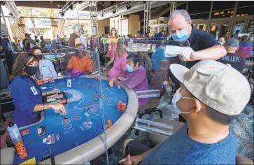  ?? Mel Melcon Los Angeles Times ?? CRAIG PHILLIPS sanitizes a partition at one of 45 card tables in what used to be the valet area of Gardens Casino in Hawaiian Gardens. Partitions and seats are sanitized each time a customer gets up, Phillips said.