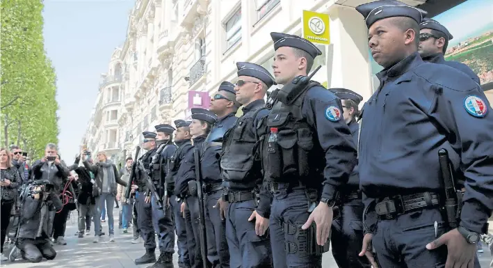  ?? AP ?? En guardia. Un grupo de policías rinde homenaje, ayer, a su compañero muerto el martes a balazos en los Campos Elíseos. Los negocios volvieron a abrir sus puertas pese al miedo.