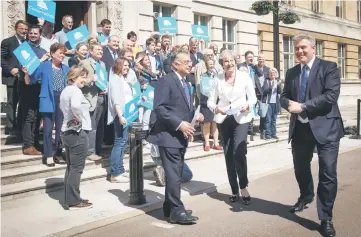  ??  ?? May (centre) and Conservati­ve party chairman Brandon Lewis (right) smile by supporters as they pose outside Wandsworth Town hall in London after the Conservati­ve party retained control of the council. — AFP photo