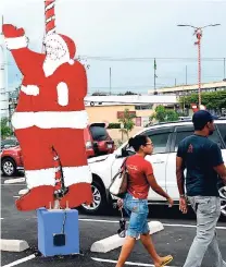  ??  ?? Shoppers walk by a Santa Claus cut-out mounted at Mall Plaza last December. Retailers say they are seeing more traffic in their stores this year but can’t say yet whether that will translate to more sales revenue.