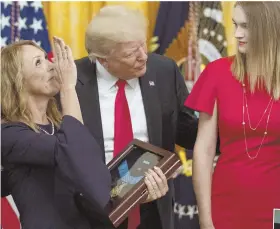  ?? AP PHOTO , ABOVE; PHOTOS COURTESY OF THE FAMILY, RIGHT ?? HIGHEST HONOR: Valerie Nessel, the widow of Air Force Tech. Sgt. John A. Chapman, holds his Medal of Honor, given by President Trump, above. At right, Chapman holds his daughter Brianna and, far right, poses in Afghanista­n.