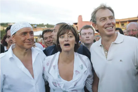  ?? AP ?? The picture of a bandana-clad Silvio Berlusconi with his guests Tony Blair, then British prime minister, and his wife Cherie in August 2004