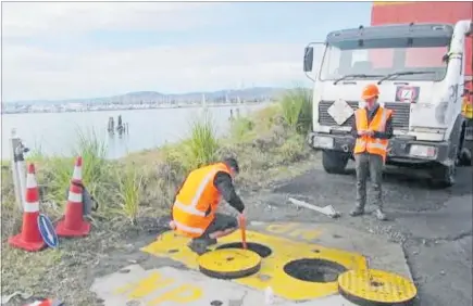  ??  ?? A Bay of Plenty Council officer examining the catchpit near the stormwater outlet that contains the shut off valve.