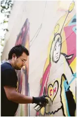  ??  ?? Freak Salazar, 24, of Durango, Mexico, paints the emblem of El Chapulin Colorado, a superhero character popular in Latin America, on Saturday on Fannin Street.