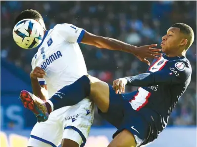  ?? (AFP) ?? Paris Saint-Germain’s French forward Kylian Mbappe (right) vying for the ball with Auxerre’s Malagasy midfielder Rayan Raveloson during the Ligue 1 match at the Parc des Princes Stadium in Paris yesterday.