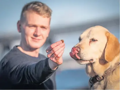  ?? Picture: Mhairi Edwards. ?? Ross Lamond with Taylor the labrador and their dog biscuits.