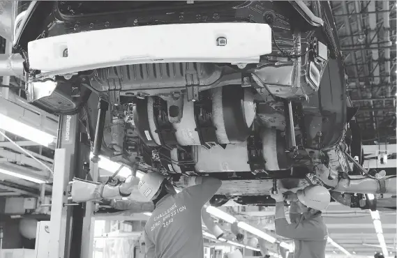  ?? YURI KAGEYAMA/THE ASSOCIATED PRESS ?? Toyota Motor Corp. workers place yellow hydrogen tanks into a Mirai fuel cell vehicle at the automaker’s Motomachi plant in Toyota, Japan. Toyota is banking on a futuristic auto technology called hydrogen fuel cells for its zero-emissions option. The biggest obstacle is not having enough hydrogen fuelling stations.