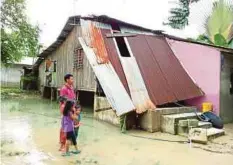  ??  ?? MOHD Fauzi melihat keadaan bumbung rumahnya yang ranap selepas dilanda banjir di Kampung Merabang.